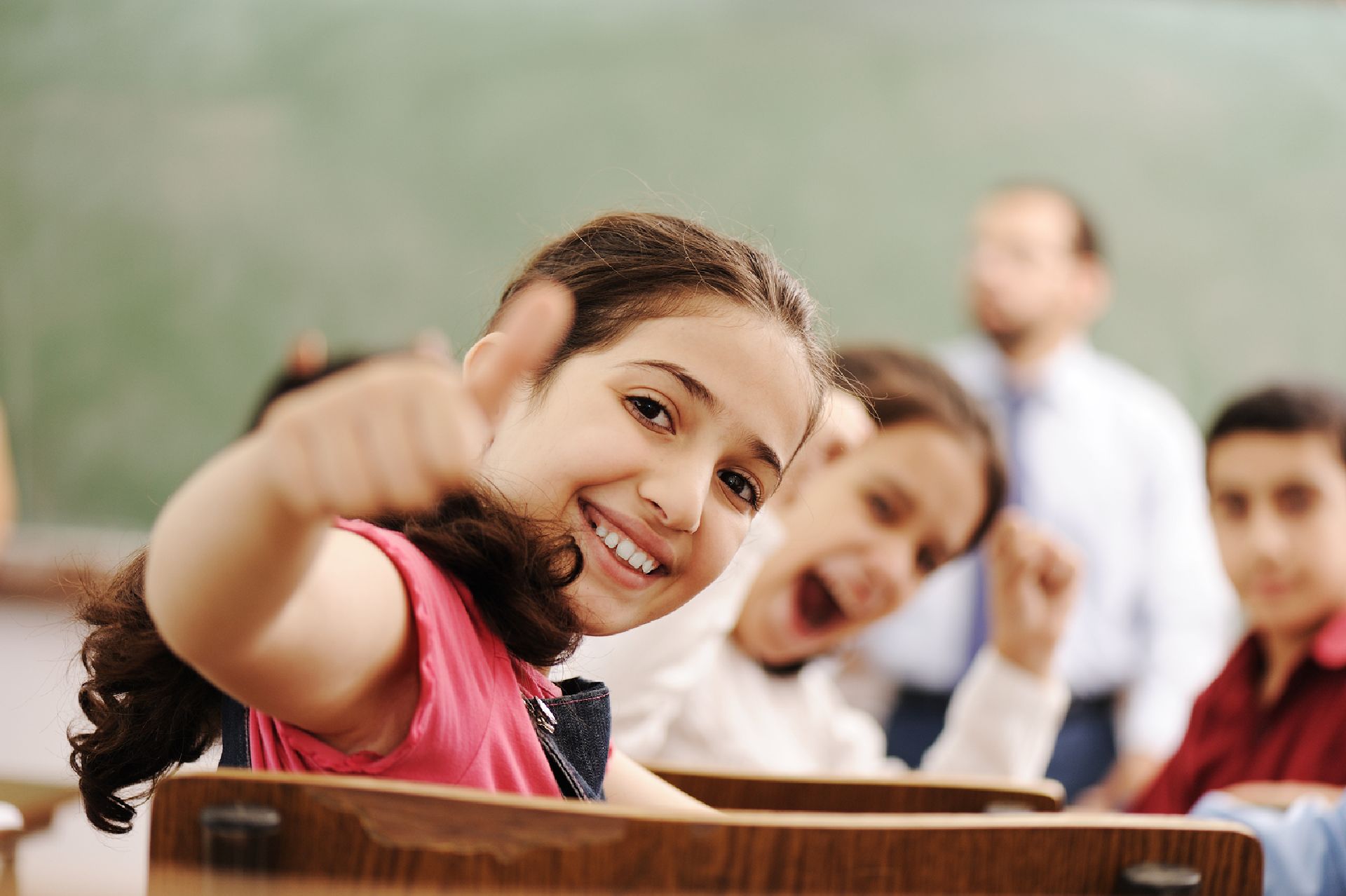 Happy children smiling and laughing in the classroom, showing thumb up, successful pupils and teacher Happy children smiling and laughing in the classroom, showing thumb up, successful pupils and teacher