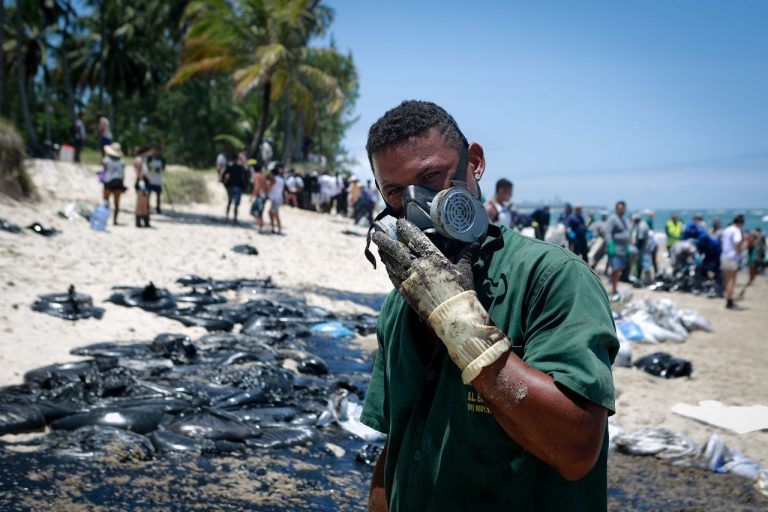 Contato prolongado com substância tem risco de câncer. Cartilha faz alerta de cuidados para voluntários que auxiliam na limpeza das praias. Foto: Leo Malafaia / AFP.