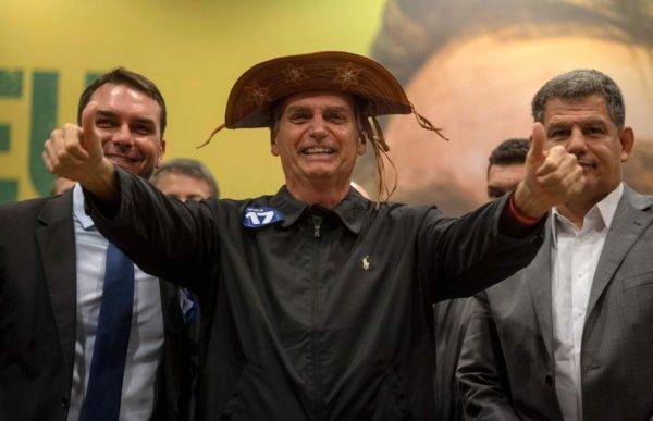 Flávio Bolsonaro, Jair Bolsonaro e Gustavo Bebianno em evento de campanha. (Crédito da foto: Mauro Pimentel / AFP)