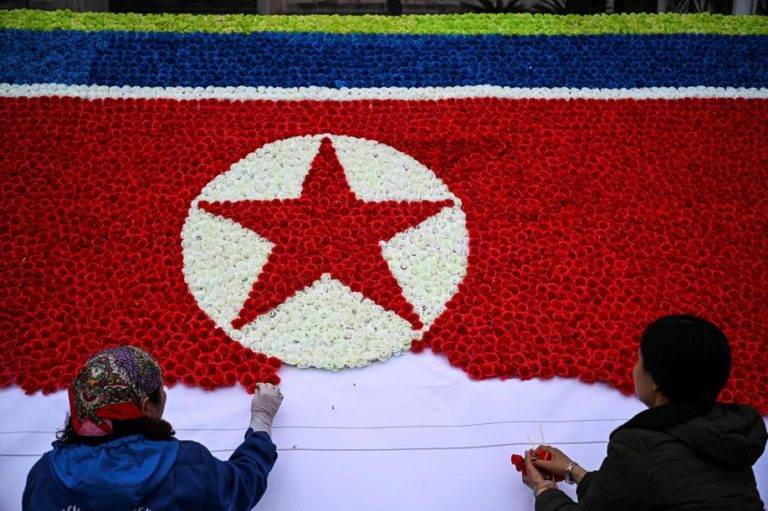Expectativas e um vencedor na próxima cúpula Trump-Kim Trabalhadores montam uma bandeira nortecoreana com flores de papel em uma rua de Hanói, Vietnã, em preparação ao encontro entre Donald Trump e Kim Jong-un nesta semana. Foto: Jewel SAMAD / AFP