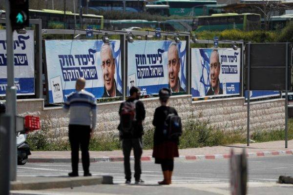 Israelenses passam por outdoors da campanha eleitoral do primeiro-ministro de Israel, Benjamin Netanyahu, em Jerusalém, em 3 de abril de 2019 | Foto: HOMAS COEX/AFP