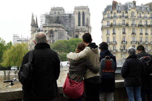 Pessoas observam os estragos em Notre-Dame de Paris, após o incêndio. Bertrand Guay/AFP
